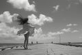 girl in a swim coverup blowing in the wind on a pier