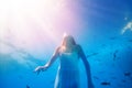Girl swim underwater with fish school, wear dress