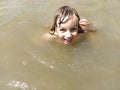 The girl is swimming, looking at the camera and laughing. Summer fun. Ocean, sea, lake or river. Turbid water in the pond. Happy Royalty Free Stock Photo