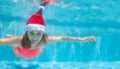 Girl swimming underwater wearing Santa Claus hat Royalty Free Stock Photo