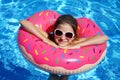 Girl swims in blue water. Outdoor pool