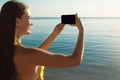 Girl In Swimsuit Holding Phone Taking Picture Of Sea Outdoors Royalty Free Stock Photo