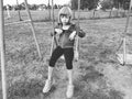 Girl on a swing. Monochrome retro photography. A child in a sports uniform is swinging. In the background is the stadium. Sadness.