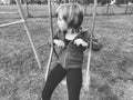 Girl on a swing. Monochrome retro photography. A child in a sports uniform is swinging. In the background is the stadium. Sadness