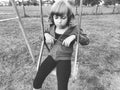 Girl on a swing. Monochrome retro photography. A child in a sports uniform is swinging. In the background is the stadium. Sadness