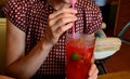 Girl in a T-shirt holding a glass with a straw and drinking fruit lemonade. homemade product of local cuisine. fair skin and slim