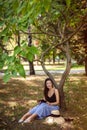 Girl with a tablet in nature sits under a tree, Work anywhere, in nature. vertical photo Royalty Free Stock Photo