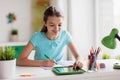 Girl with tablet pc writing to notebook at home Royalty Free Stock Photo