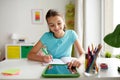 Girl with tablet pc writing to notebook at home Royalty Free Stock Photo