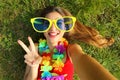 Girl take self portrait after Carnival party. Selfie young woman with big funny sunglasses and carnival garland lying on grass