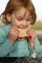 Girl takes big bite of sandwich Royalty Free Stock Photo