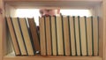 Girl takes a book from a bookshelf close-up. Inside view