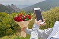 Girl takes a bouquet of red flowers and fruits on a phone camera Royalty Free Stock Photo