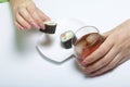 The girl takes a glass of whiskey from the table with ice. Another hand takes from the plate of sushi. Rest of the day off. Royalty Free Stock Photo