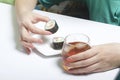 The girl takes a glass of whiskey from the table with ice. Another hand takes from the plate of sushi. Rest of the day off. Royalty Free Stock Photo