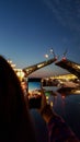 Girl takes photo on phone breeding Palace Bridge in St. Petersburg during White Nights. View from Neva River to raised bridge.