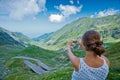 The girl takes a photo of Transfagarasan mountain road. Romania.