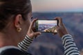 The girl takes photos or films the Grand Canyon at sunset