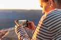 The girl takes photos or films the Grand Canyon at sunset