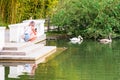 A girl takes pictures on a smartphone of swans floating in a pond in the Park of Southern Cultures, Adler, Sochi, Russia