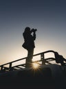 Girl takes pictures standing on car roof rack Royalty Free Stock Photo