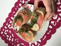 The girl takes the sandwich from the plate. Sandwiches with salmon, decorated with greens and lemon. Sandwiches on a plate, standi