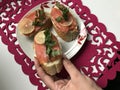 The girl takes the sandwich from the plate. Sandwiches with salmon, decorated with greens and lemon. Sandwiches on a plate, standi