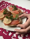 The girl takes the sandwich from the plate. Sandwiches with salmon, decorated with greens and lemon. Sandwiches on a plate, standi