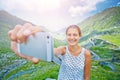 The girl takes a selfie photo of Transfagarasan mountain road. Romania. Royalty Free Stock Photo