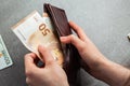 Girl is taking out a banknote of fifty euros from brown leather wallet. Hands, money and wallet close-up. charity. gray background Royalty Free Stock Photo