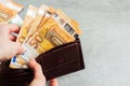 Girl is taking out a banknote of fifty euros from brown leather wallet. Hands, money and wallet close-up. charity. gray background Royalty Free Stock Photo