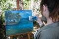 Girl taking photo of painting on tripod in garden