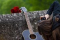 Girl taking photo of guitar and red roses on the old bridge wall Royalty Free Stock Photo