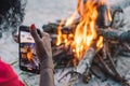 Girl taking photo with smartphone while preparing coffee to tea on a bonfire