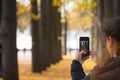 Girl taking photos on her phone in autumn park Royalty Free Stock Photo