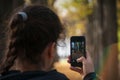 Girl taking photos on her phone in autumn park Royalty Free Stock Photo