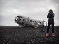 Girl is taking picture of abandoned crashed plane in Iceland