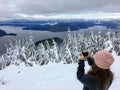 A girl taking a picture atop Cypress Mountain overlooking the ocean below. Royalty Free Stock Photo