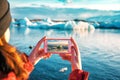 Girl taking a picture of a blue iceberg in Iceland Royalty Free Stock Photo