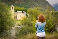 Girl taking a picture with a smartphone of the romanesque church of Sant Feliu de Barruera, in catalan Pyrenees. Royalty Free Stock Photo