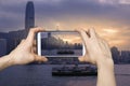 Pictures on mobile smart phone in Hong Kong`s Victoria Harbour in sunrise