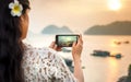 Girl taking seaside sunset picture with smartphone