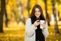 Girl taking selfie on phone with coffee on yellow sunny park Royalty Free Stock Photo