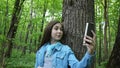 Girl taking selfie photo smartphone at park in summer. Posing and smiling. Video footage.