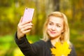 Girl taking a selfie on smart phone in autumn park Royalty Free Stock Photo