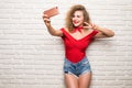 Girl taking selfie smart phone camera excited happy smile woman over white brick office wall Royalty Free Stock Photo