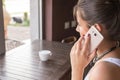 Girl talk to a cell phone in a coffee shop. View behind girl shoulder