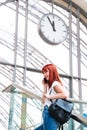 Girl talking on phone on background with wall clock on railway station