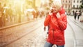 Girl talking on the phone on the street. Portrait of pretty smiling young woman in red bright raincoat. Sunny raining Royalty Free Stock Photo