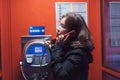 A girl is talking on a public telephone at night on the street. Royalty Free Stock Photo